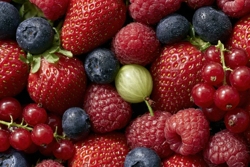 Closeup of mixed fresh berries including strawberries blueberries raspberries and redcurrants piled together