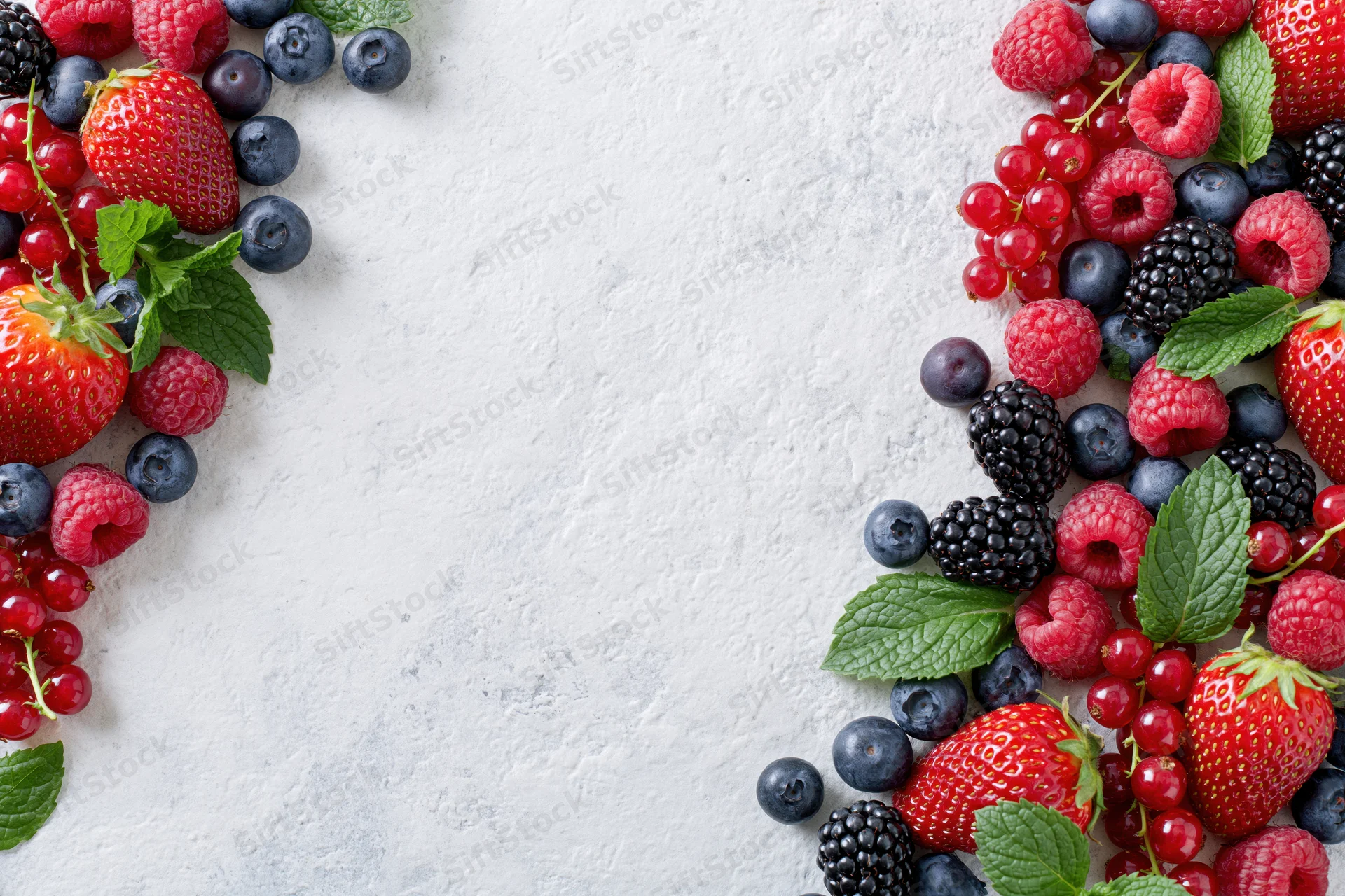 Mixed fresh berries arranged along left and right edges on textured white surface with central copyspace