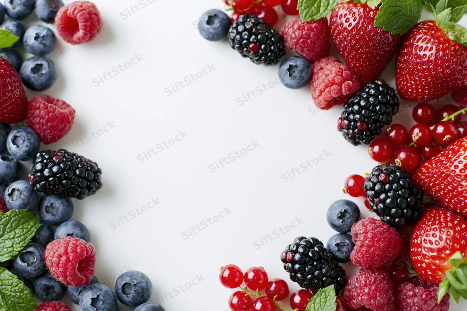 Mixed fresh berries arranged in two clusters framing a white copyspace on a flat surface