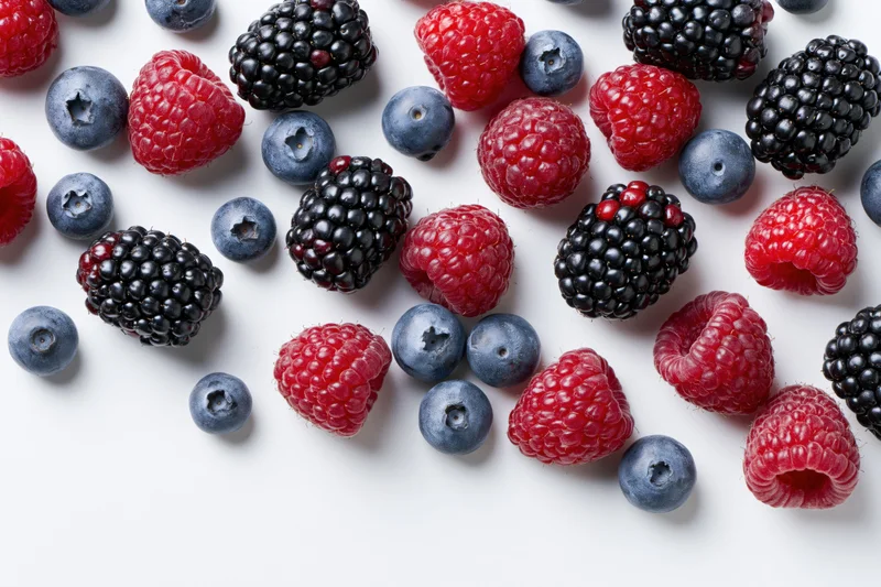 Mixed fresh berries scattered across a white surface