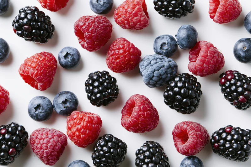 Mixed fresh berries scattered across a white surface