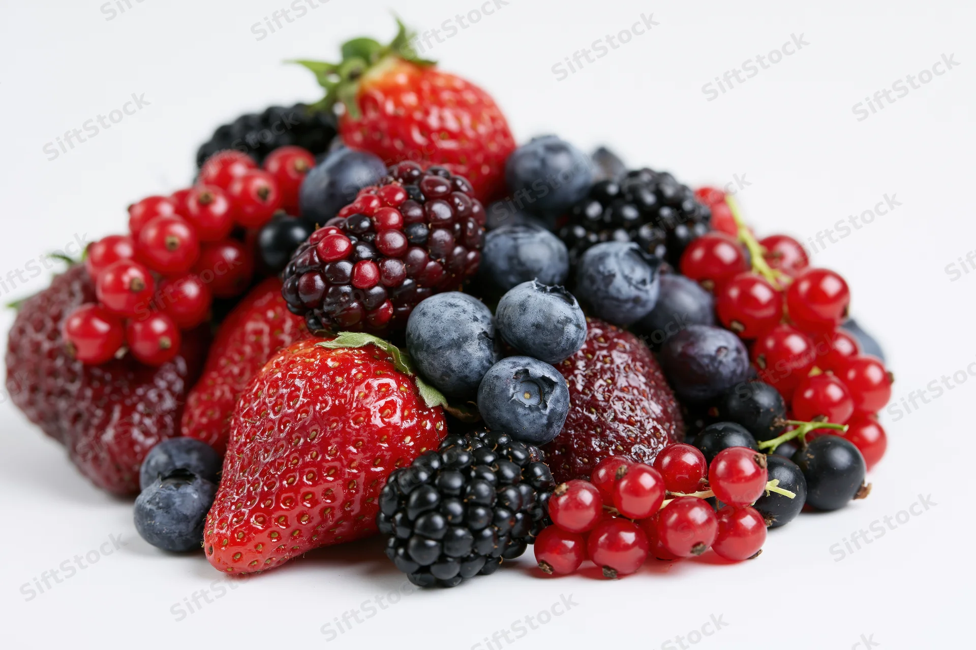 Mixed fresh berries including strawberries blueberries blackberries and redcurrants on white background