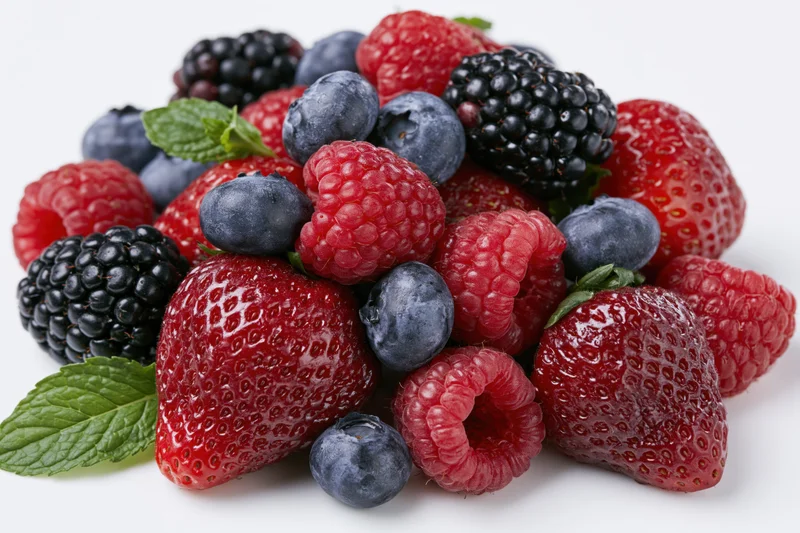 Mixed fresh berries including strawberries raspberries blackberries and blueberries with mint leaves on white background