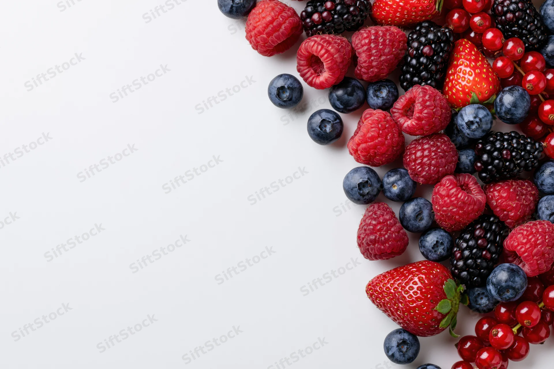 Mixed fresh berries arranged along the right edge on a white surface