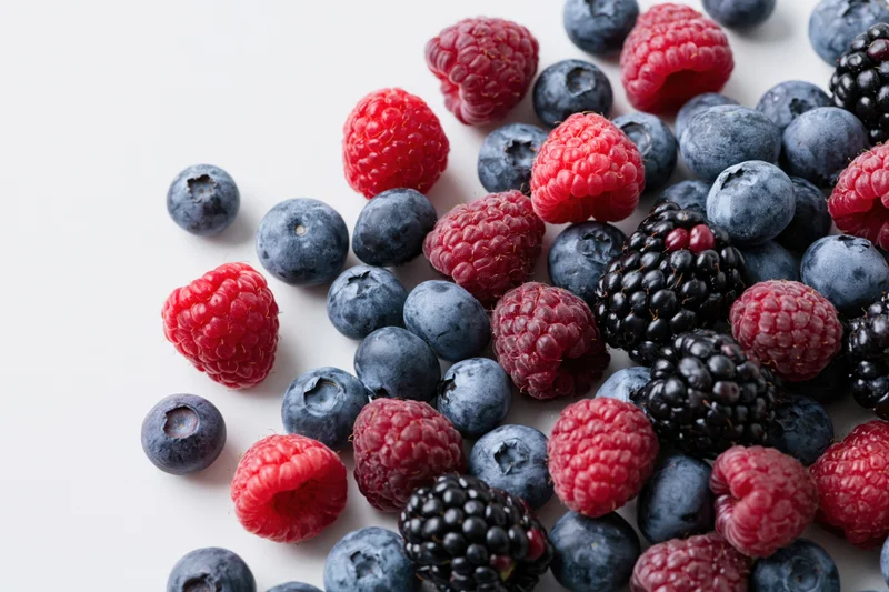 Mixed fresh blueberries raspberries and blackberries scattered