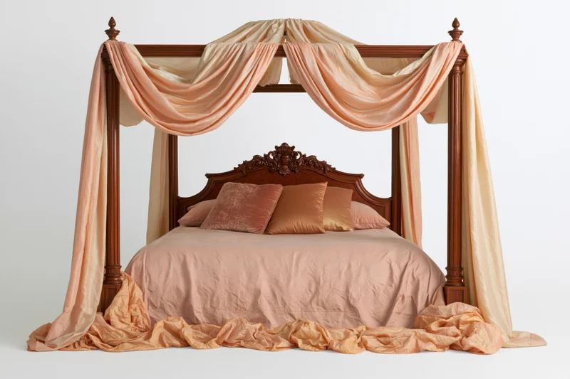 Ornate wooden four-poster canopy bed with draped peach fabric and pillows on white background