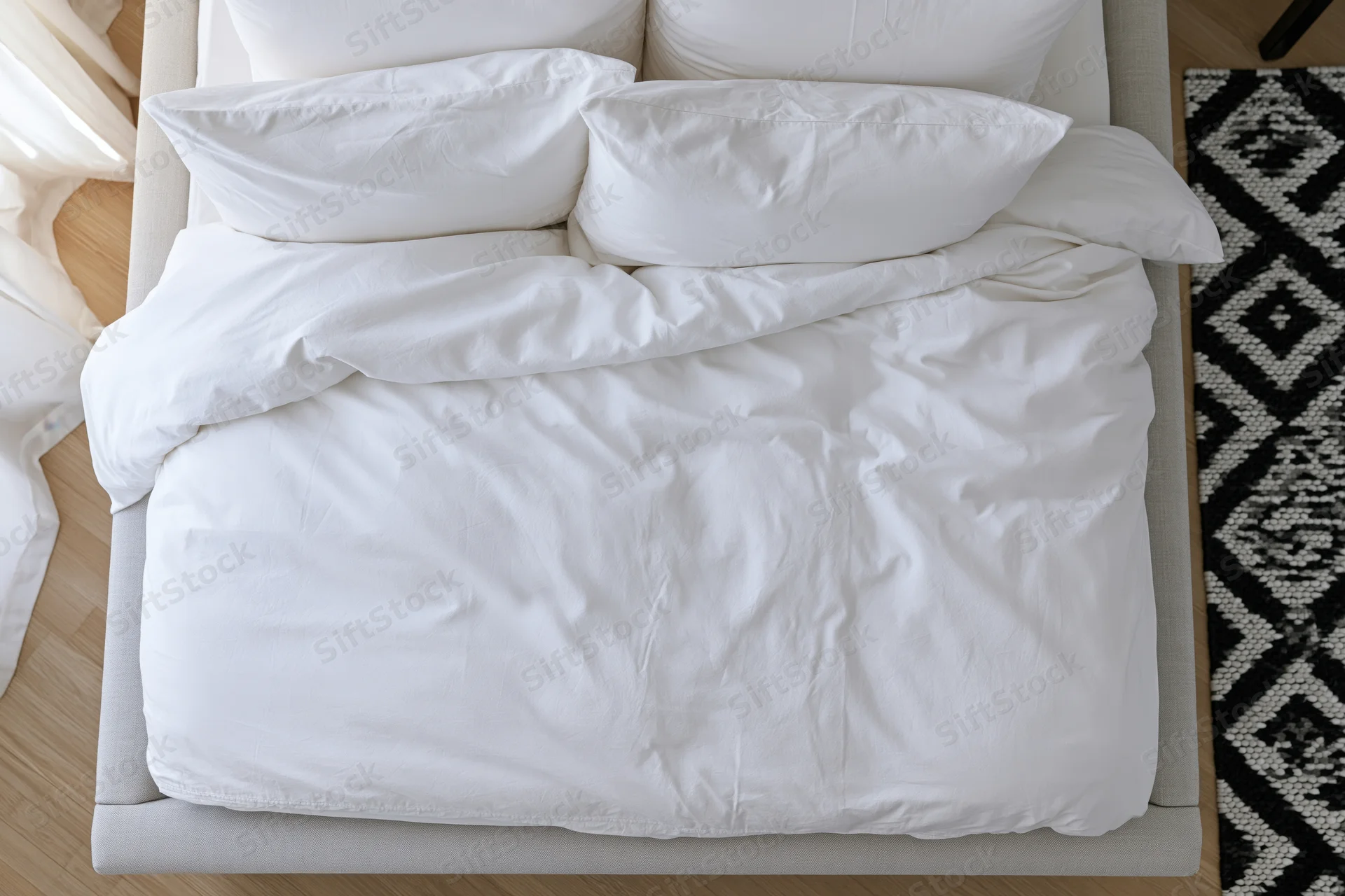 Overhead view of a neatly made bed with white cotton bedding in a modern bedroom