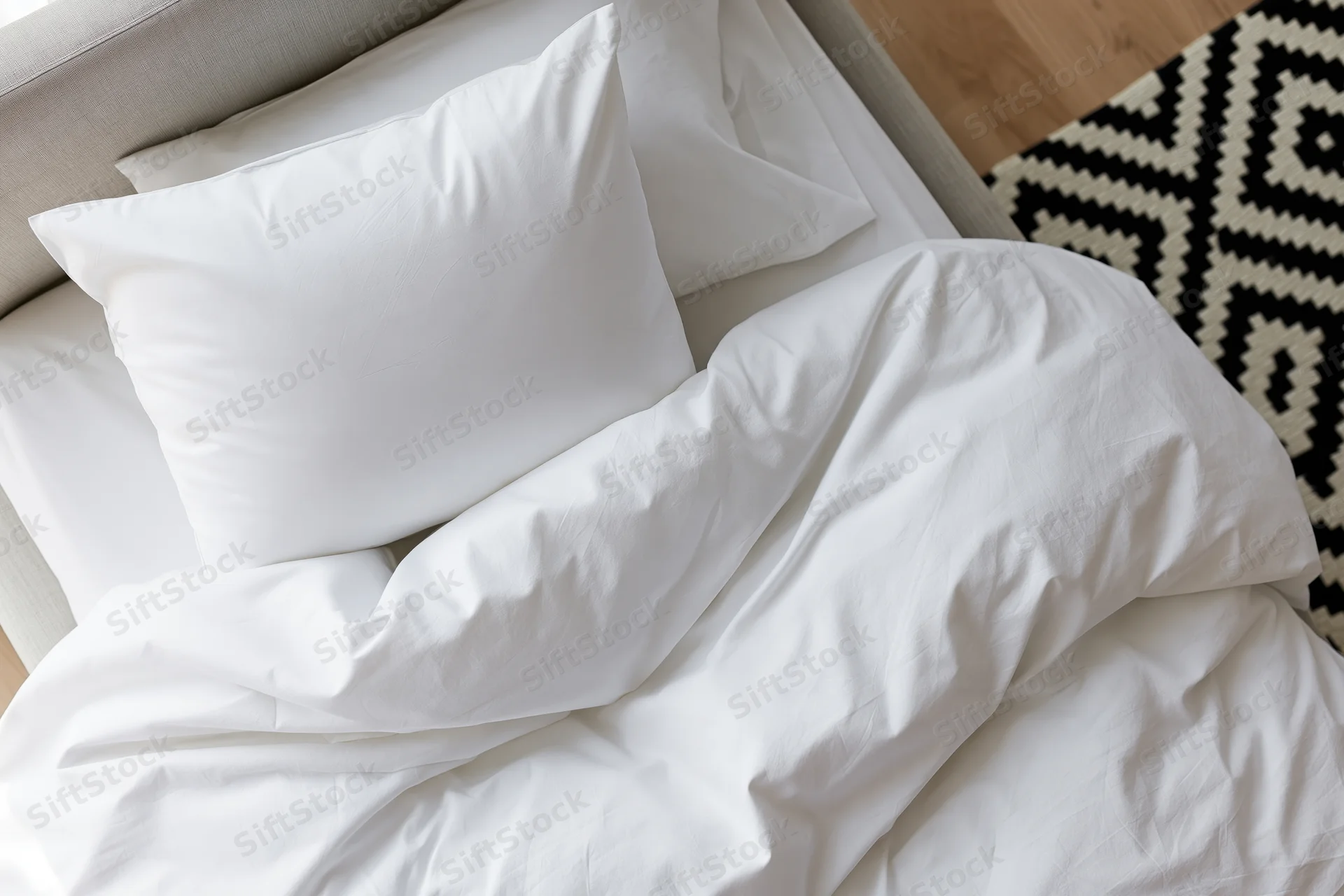 Overhead view of rumpled white cotton bedding on a bed in a bedroom