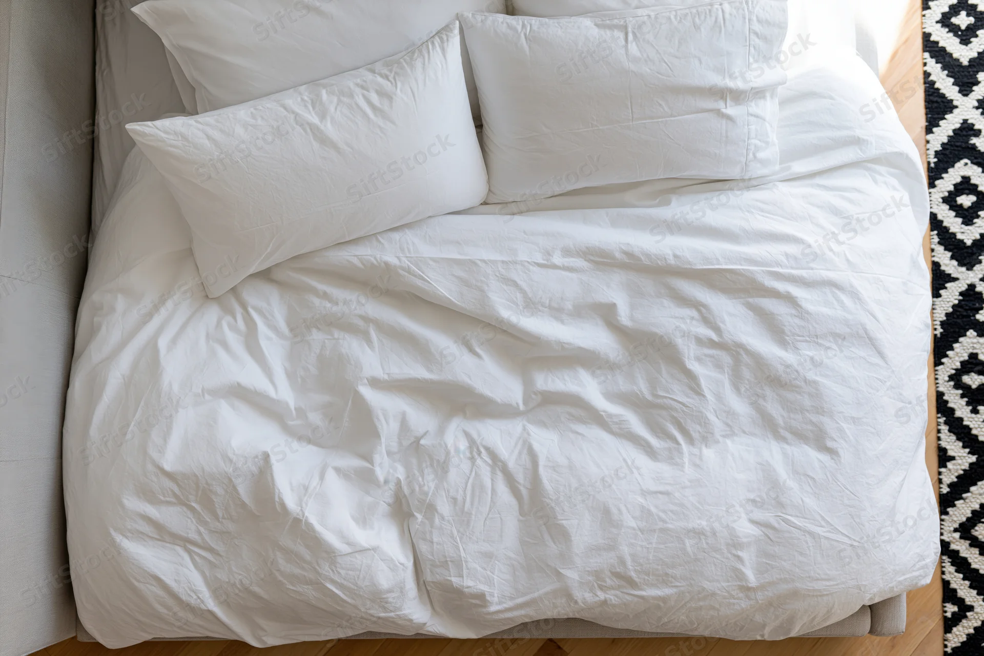 Overhead view of a rumpled white cotton bed with pillows in a bedroom