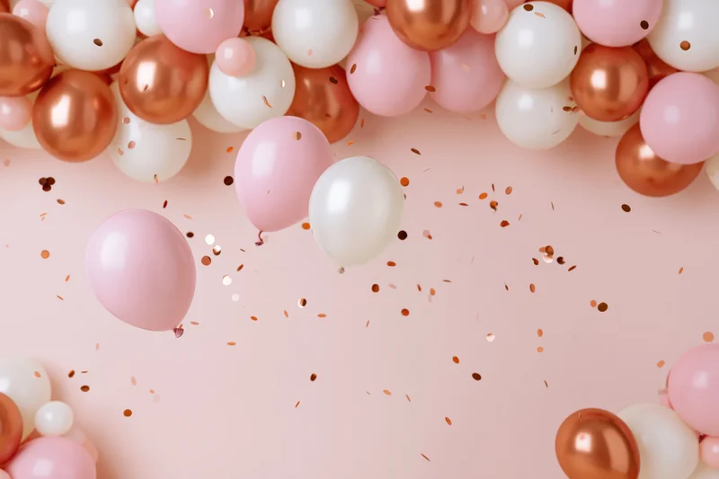 Pink white and rose gold balloons arranged in clusters with confetti on a pastel background