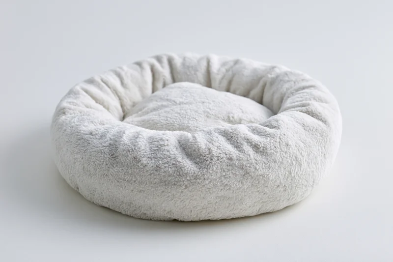 Round plush pet bed on plain white surface