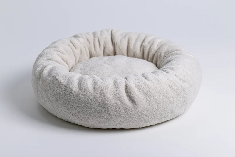 Round plush pet bed on plain white surface