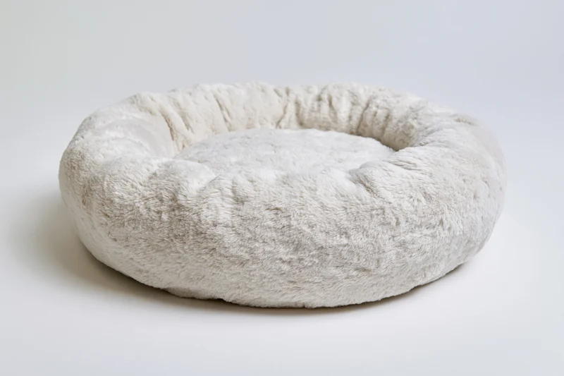 Round plush pet bed on plain white surface
