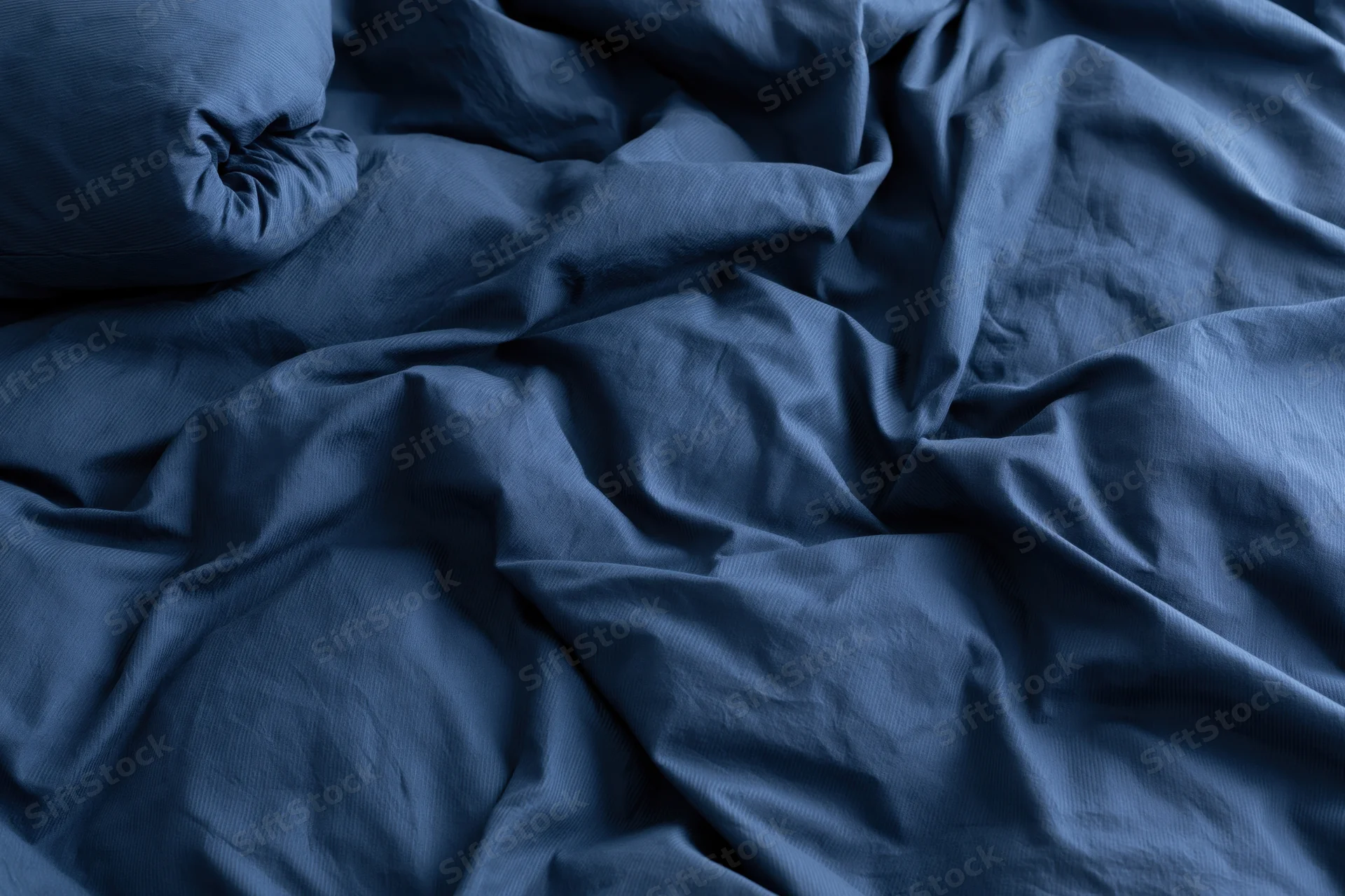 Rumpled navy blue duvet cover filling the frame with crumpled fabric texture