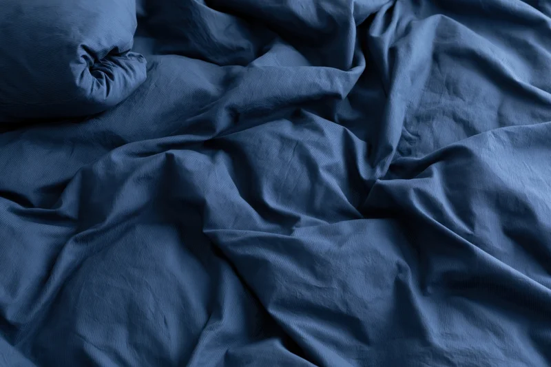 Rumpled navy blue duvet cover filling the frame with crumpled fabric texture