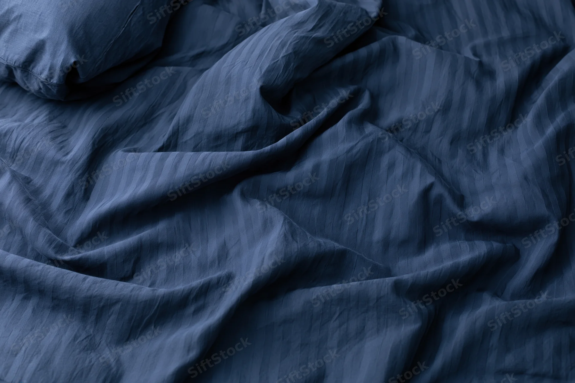 Rumpled navy blue duvet cover filling the frame with visible wrinkles and texture