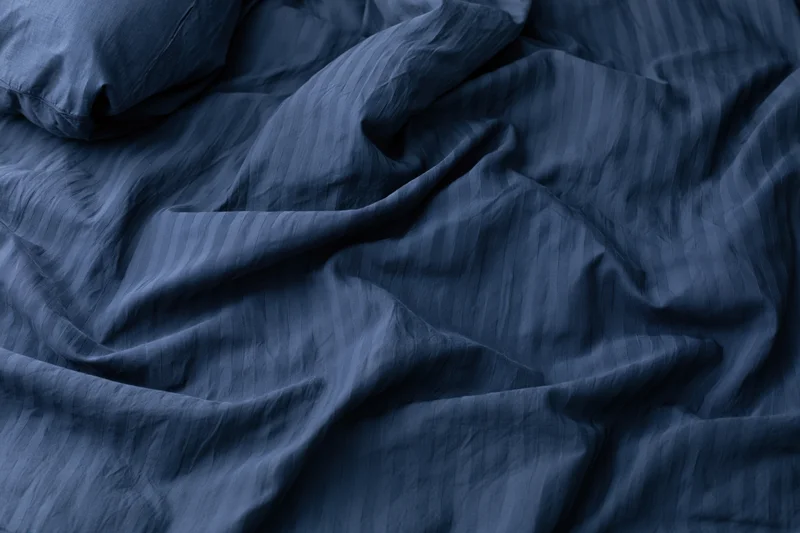 Rumpled navy blue duvet cover filling the frame with visible wrinkles and texture