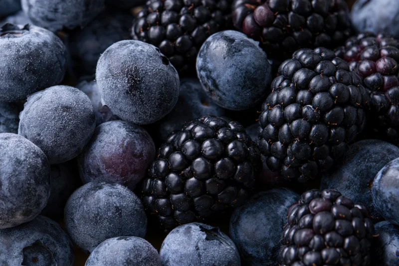 Frozen blueberries and blackberries piled together in a close-up view