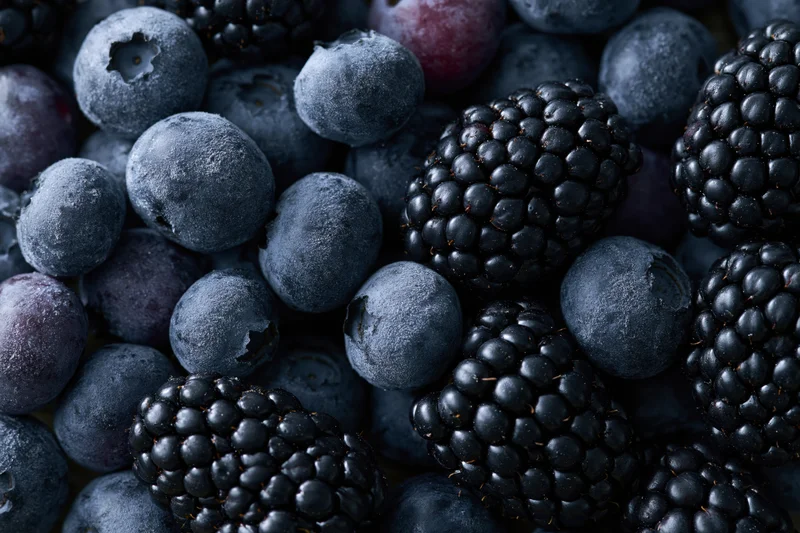 Closeup of scattered blueberries and blackberries piled together filling the frame
