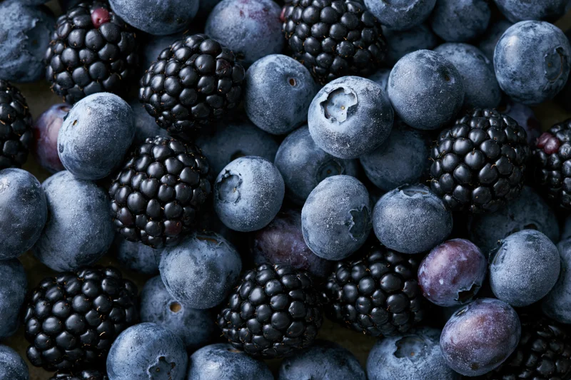 Blueberries and blackberries piled together in a close-up view