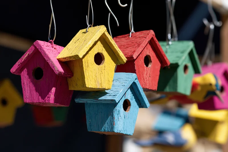 Colorful wooden birdhouses hanging from wire hooks for garden decoration