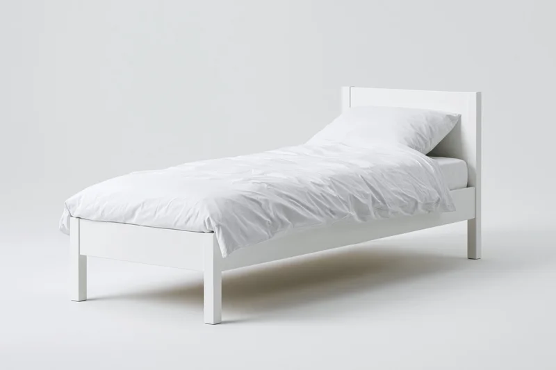White wooden single bed with rumpled white bedding on plain white background