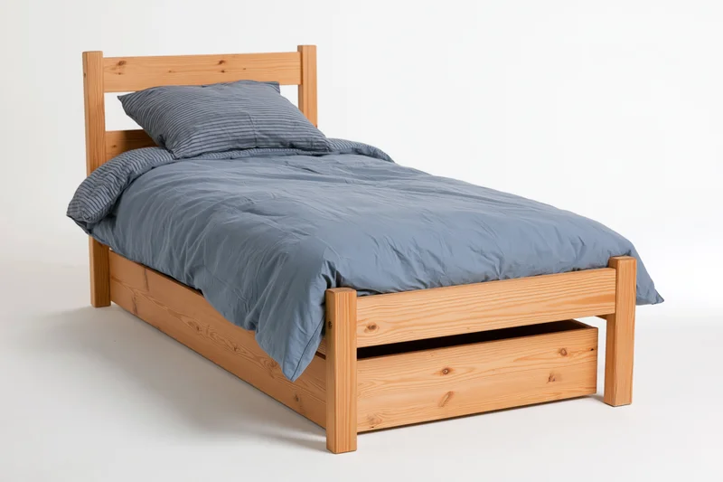 Wooden bed with headboard and under-bed drawer neatly arranged in studio setting