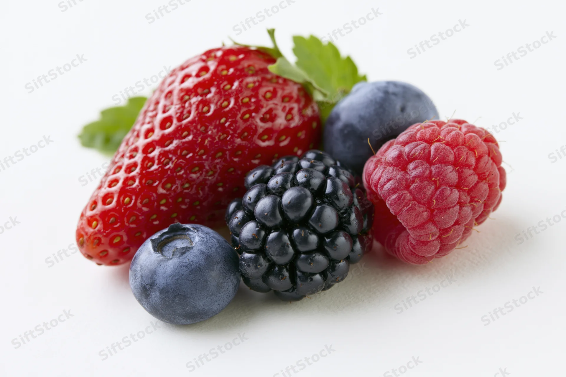 Cluster of fresh mixed berries including strawberry, blueberry, blackberry and raspberry on white background
