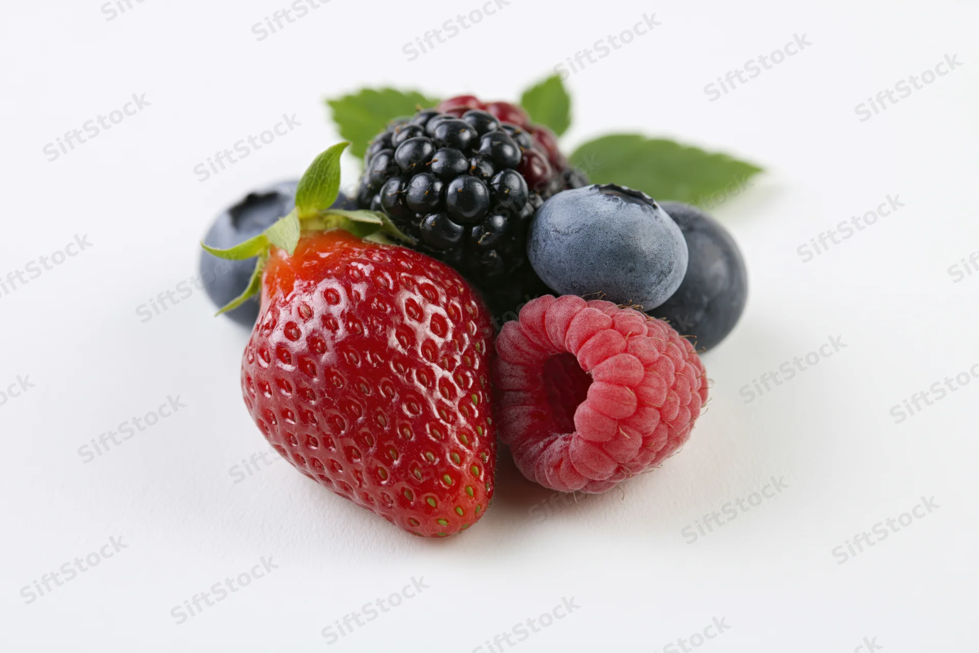 A cluster of fresh mixed berries including strawberry, blueberry, raspberry and blackberry on a white background