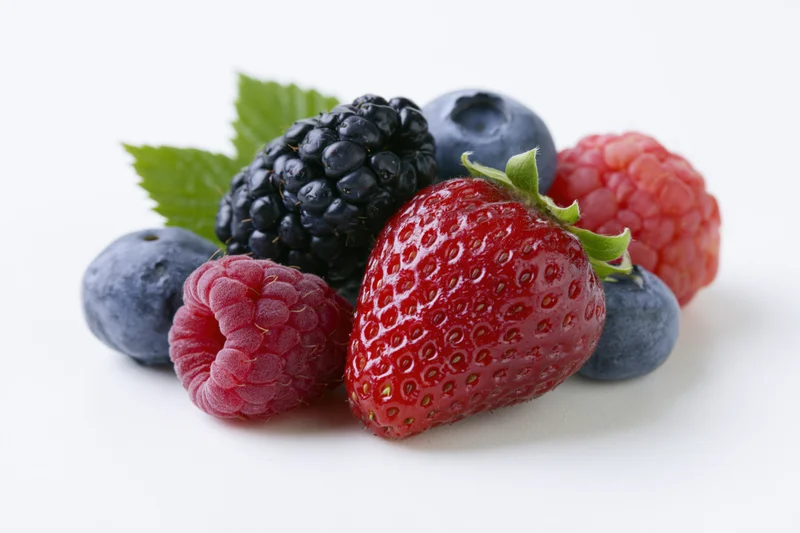 Cluster of fresh mixed berries including strawberry, raspberry, blueberry and blackberry on white background