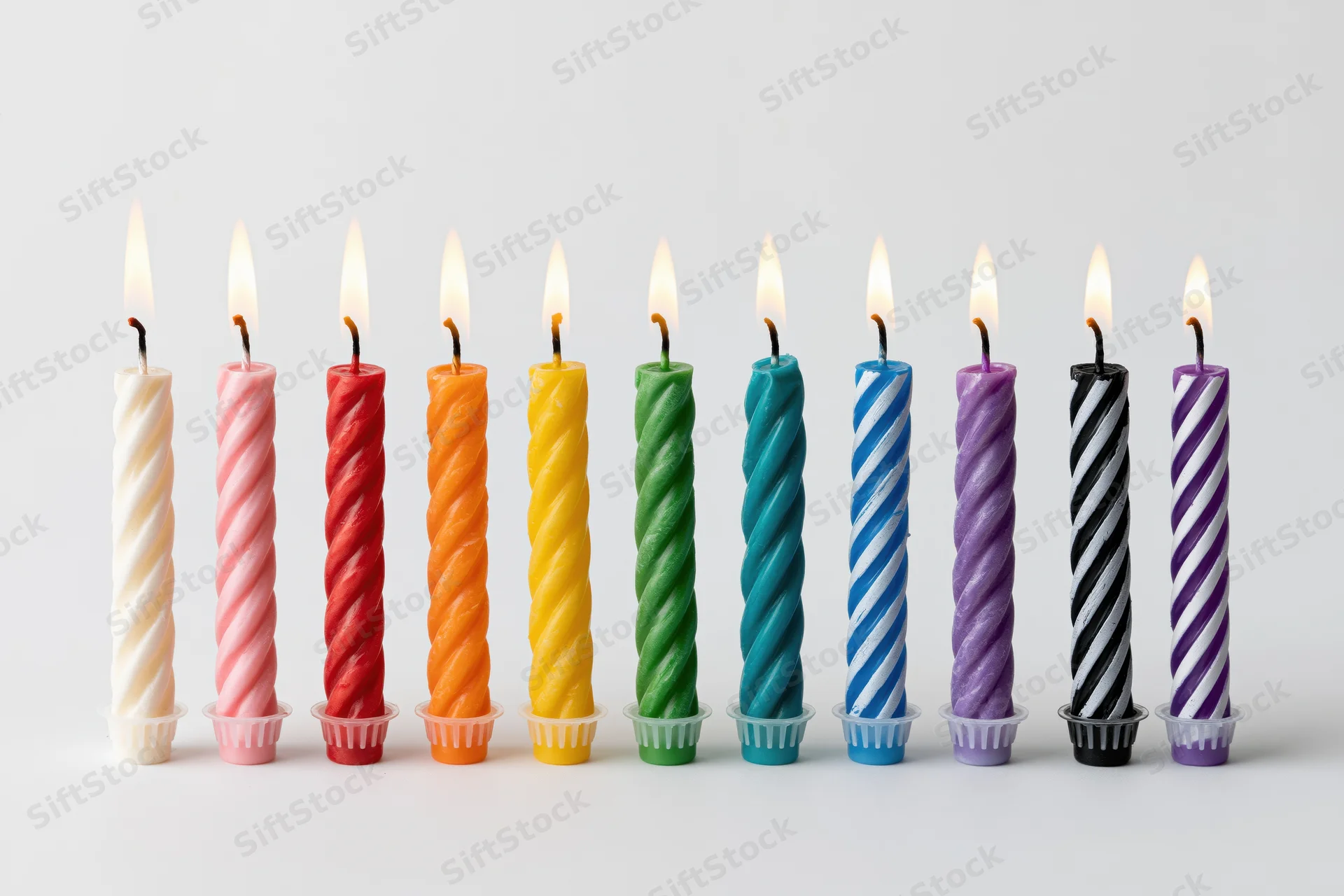 Ten lit birthday candles in a straight row on a white background