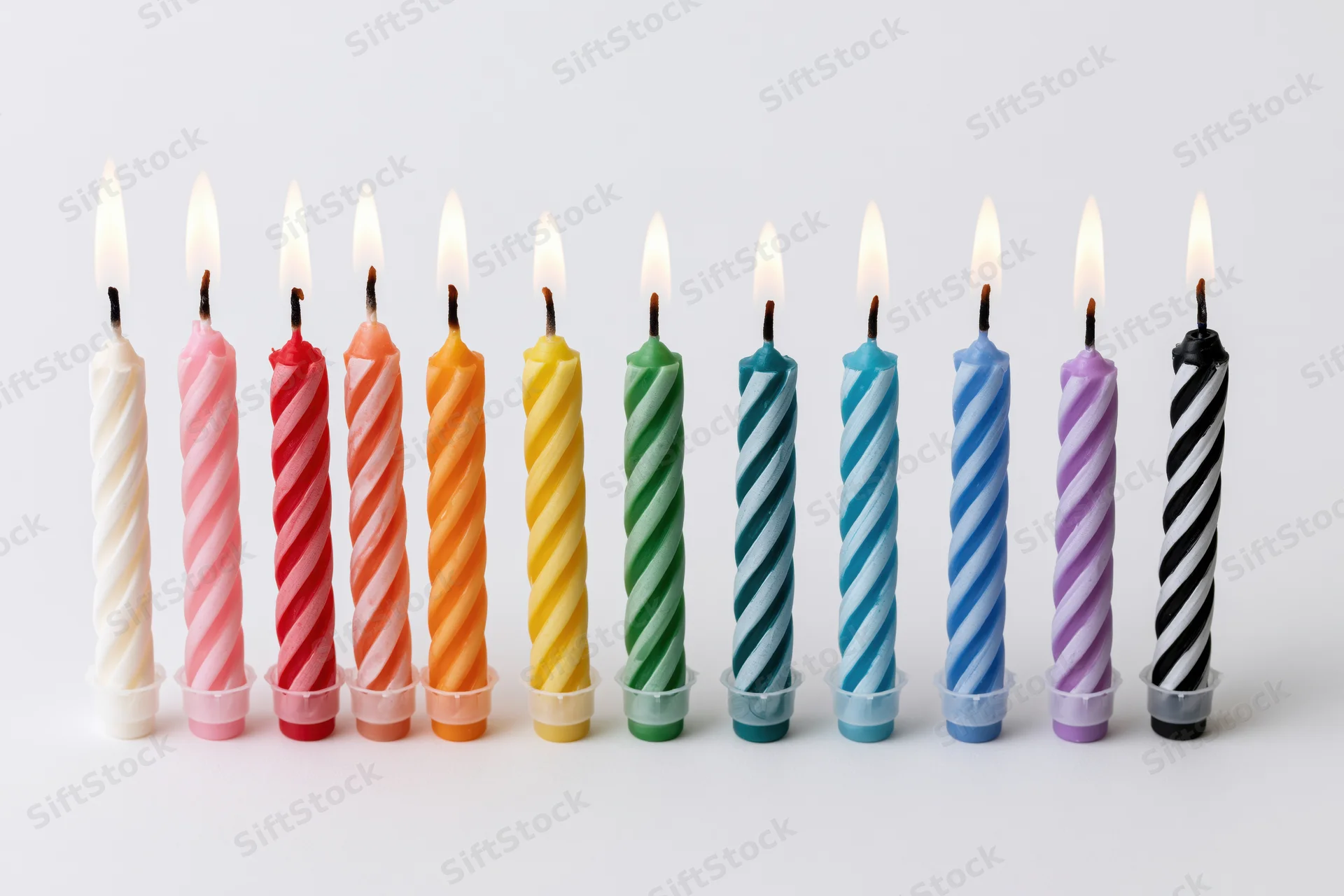 Ten lit birthday candles in a straight row against a pure white background