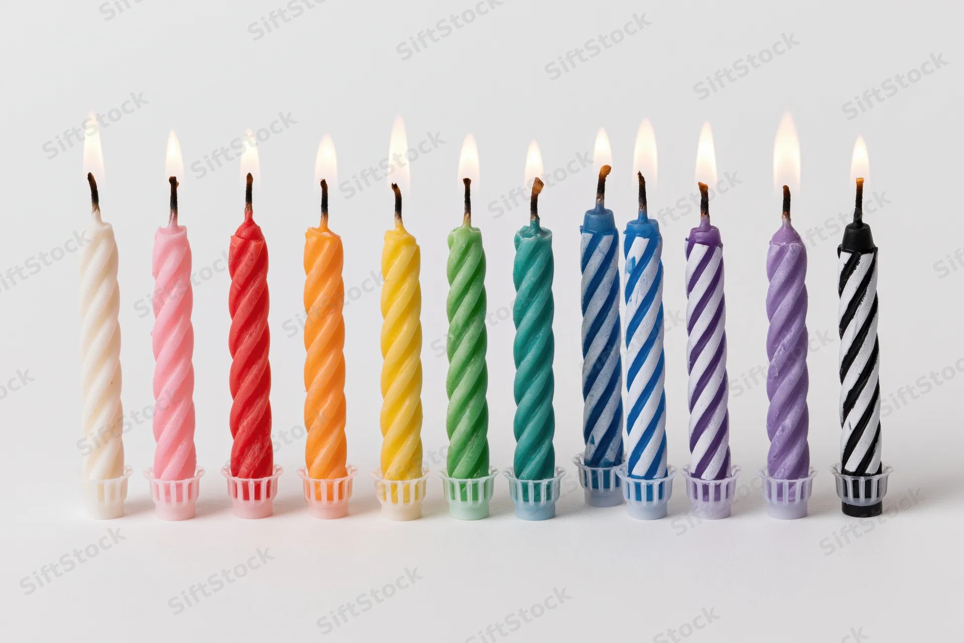 Ten lit birthday candles in a straight row against a pure white background