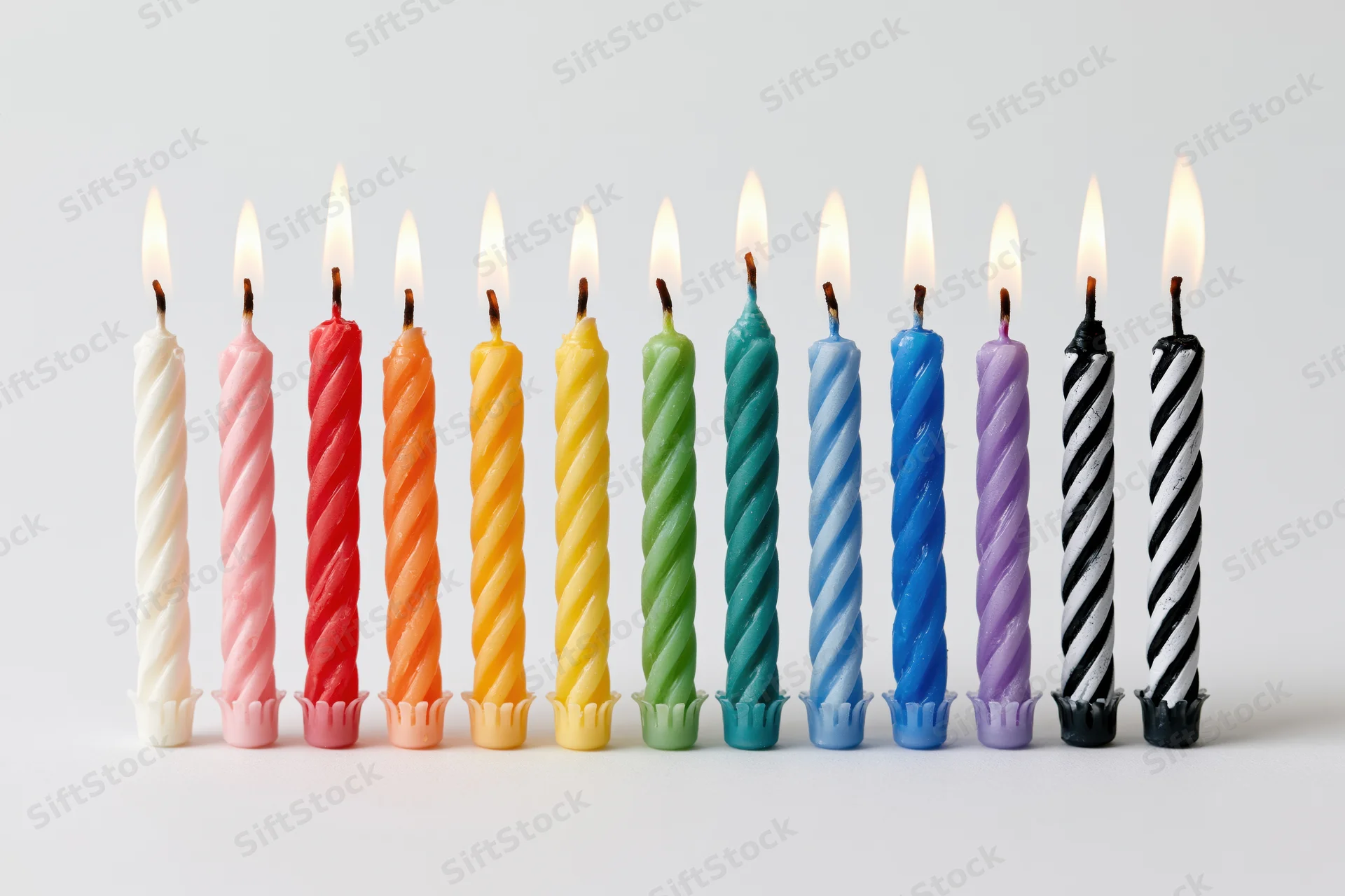 Ten lit birthday candles in a straight row against a pure white background