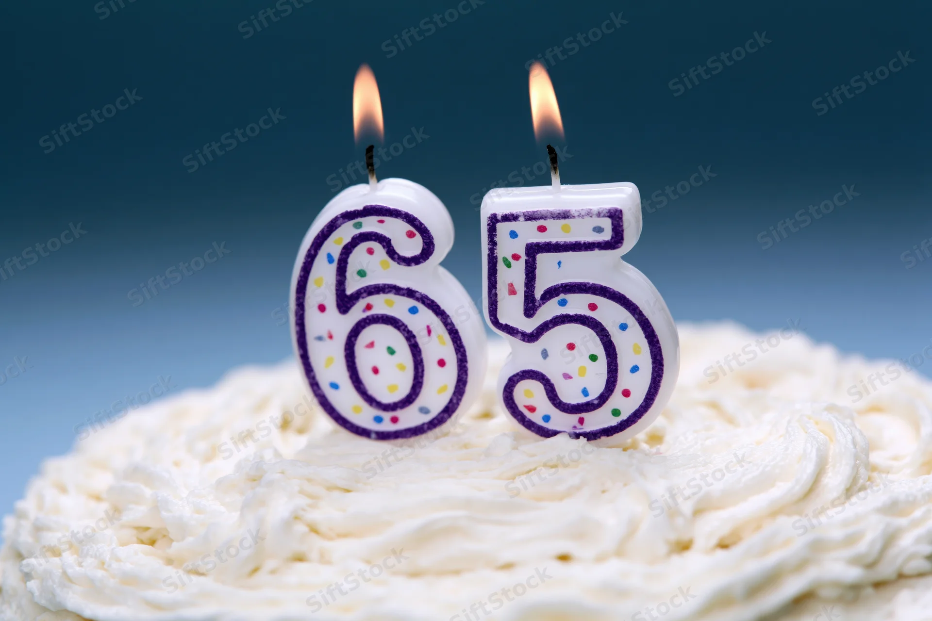Number-shaped birthday candles lit on a white-frosted cake