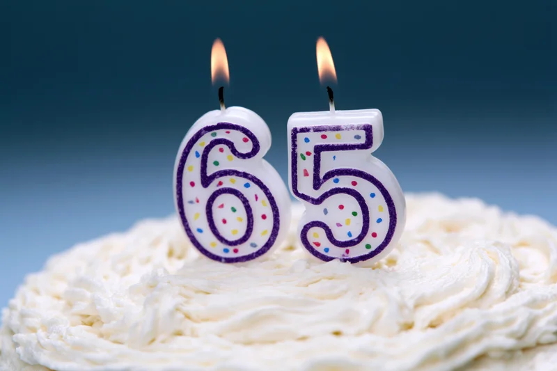 Number-shaped birthday candles lit on a white-frosted cake