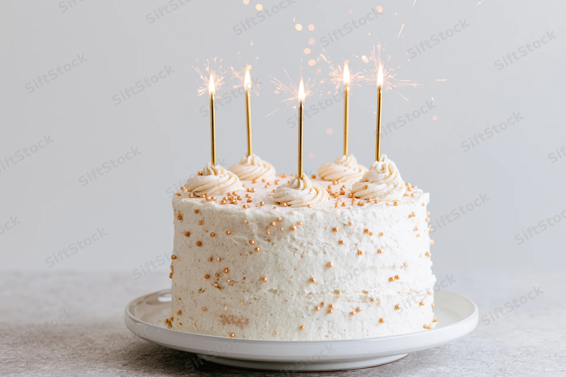 White celebration cake with lit sparklers on a ceramic stand