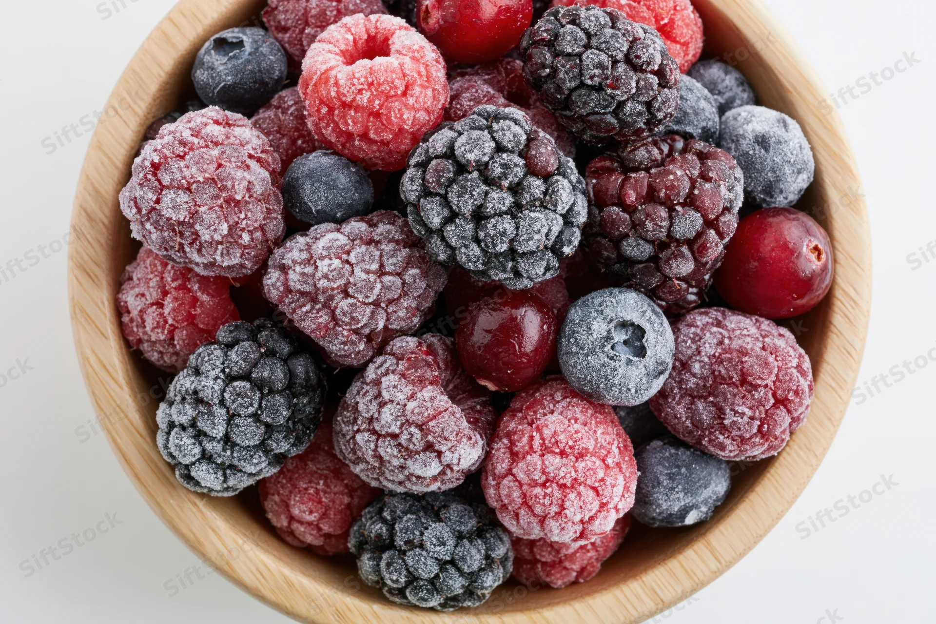 Frozen berries in a wooden bowl viewed from above