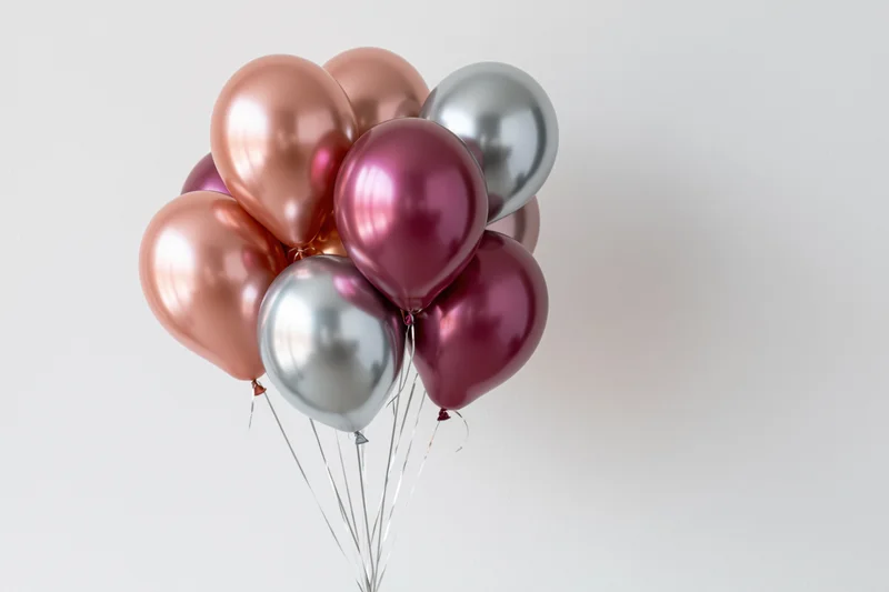 Metallic balloons clustered together floating against a white background with copyspace