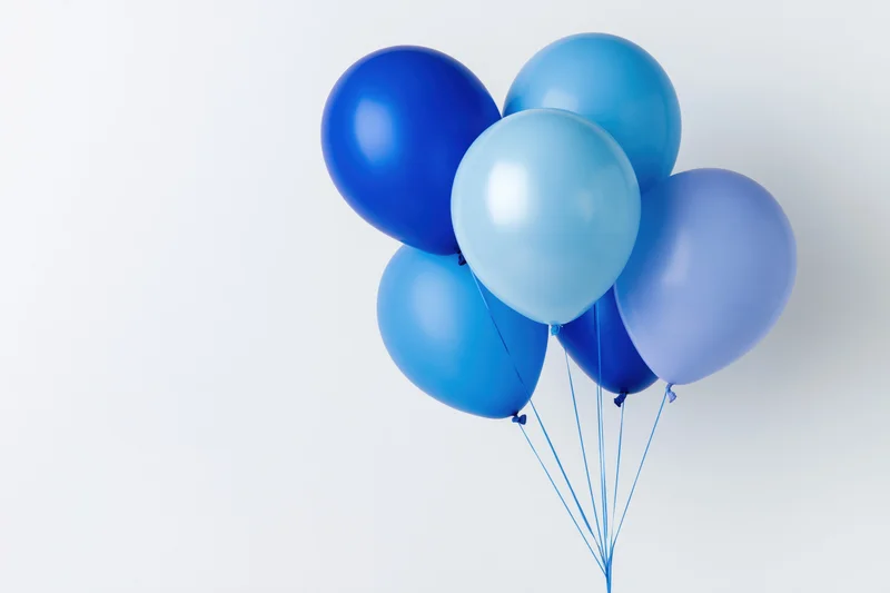 Cluster of blue helium balloons tied together against white background with copyspace