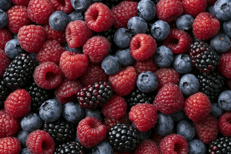 Closeup of fresh raspberries blueberries and blackberries in a dense flat lay arrangement
