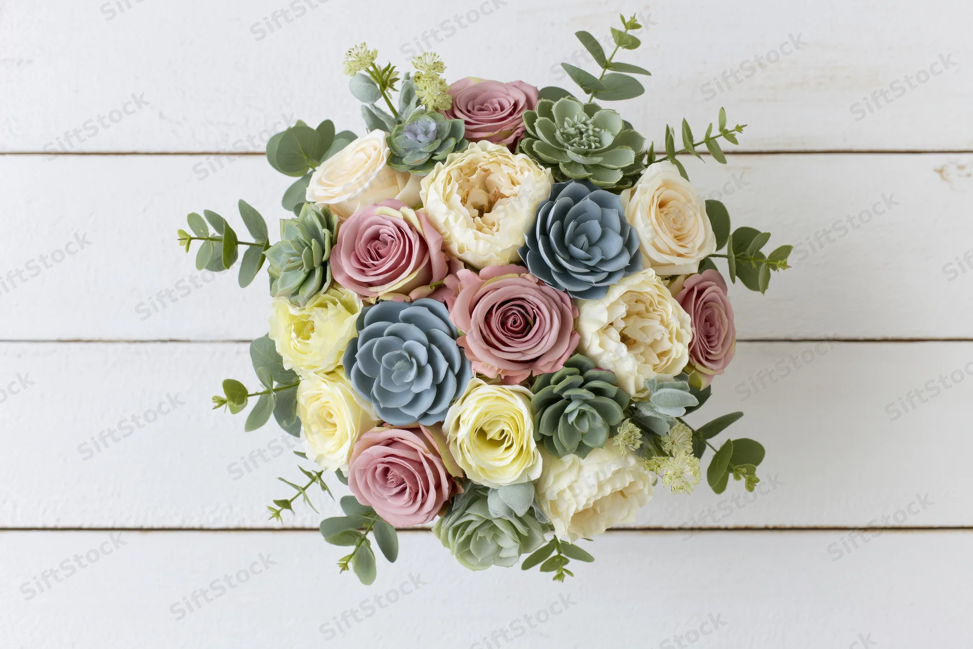 Mixed floral bouquet arranged in rounded dome shape on white wooden surface