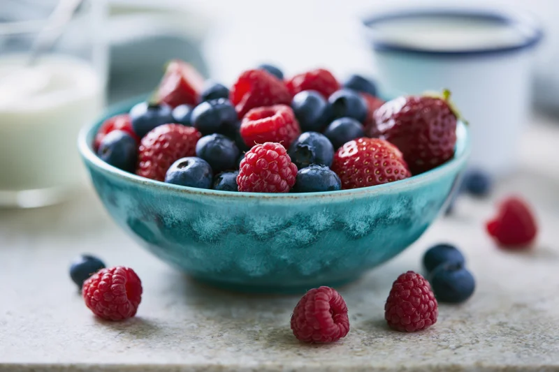 Mixed berries in a turquoise ceramic bowl on a kitchen countertop