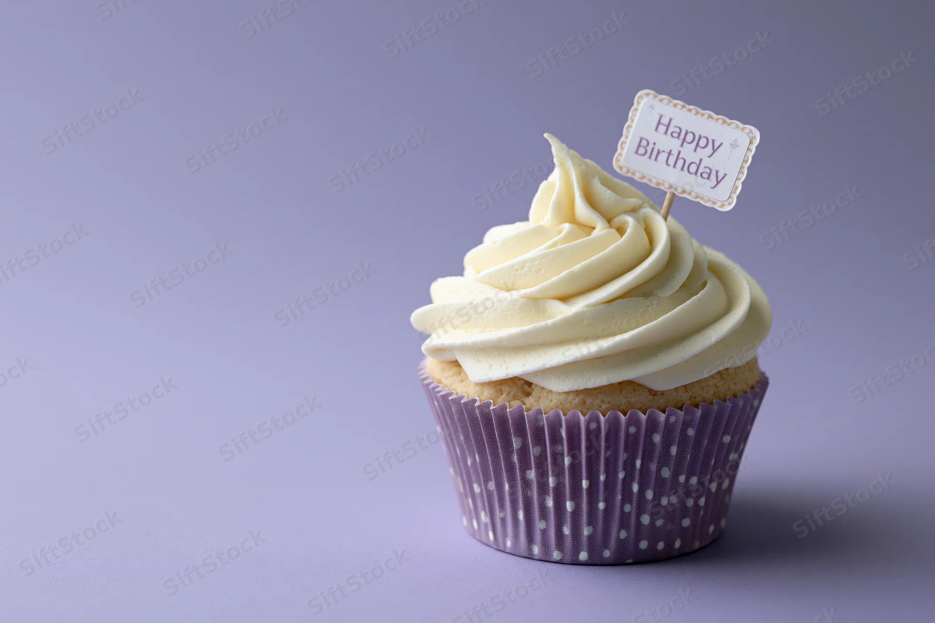Single cupcake with white cream frosting and happy birthday flag in purple polka dot liner on lavender background