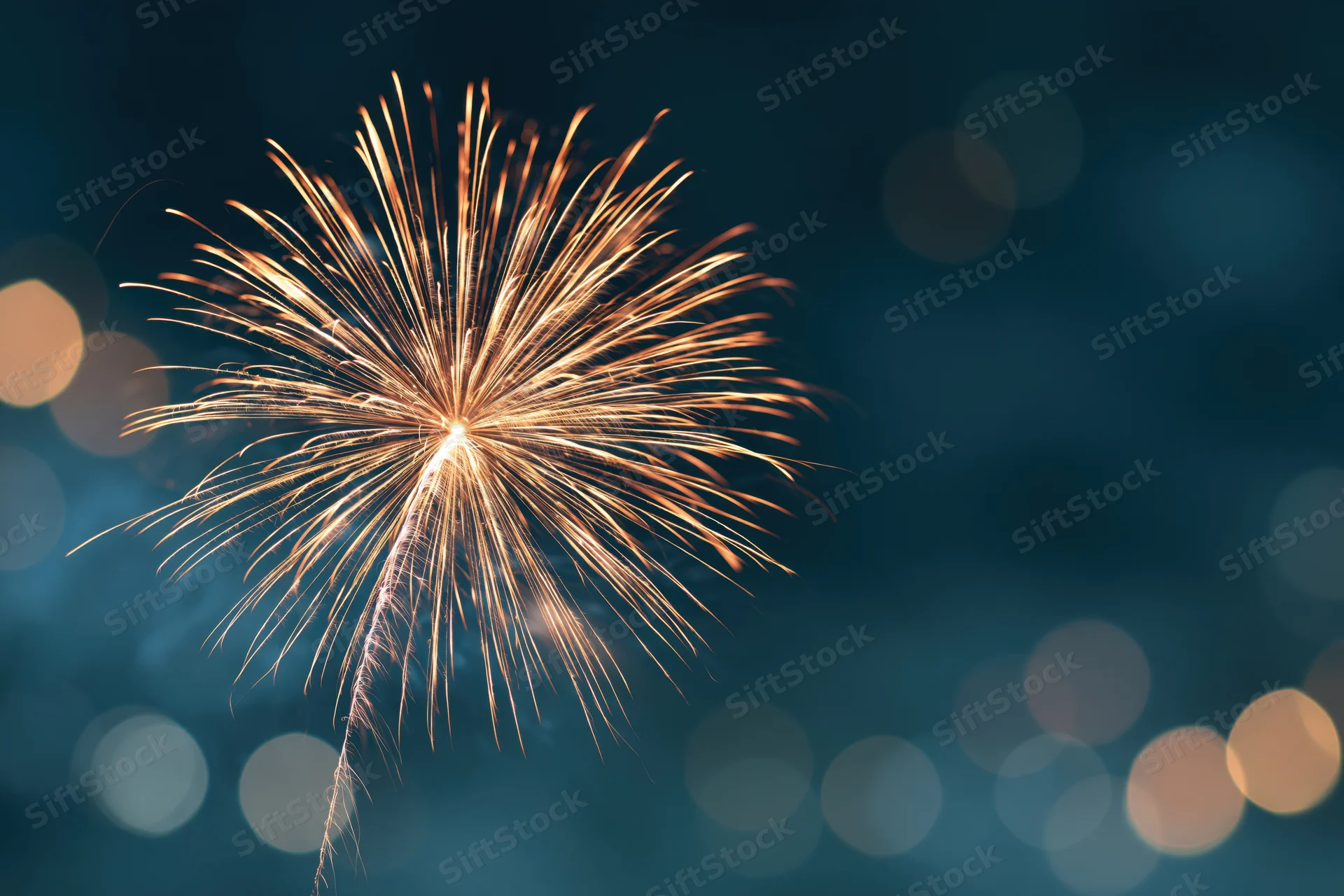Golden firework bursting in the night sky with bokeh lights in the background