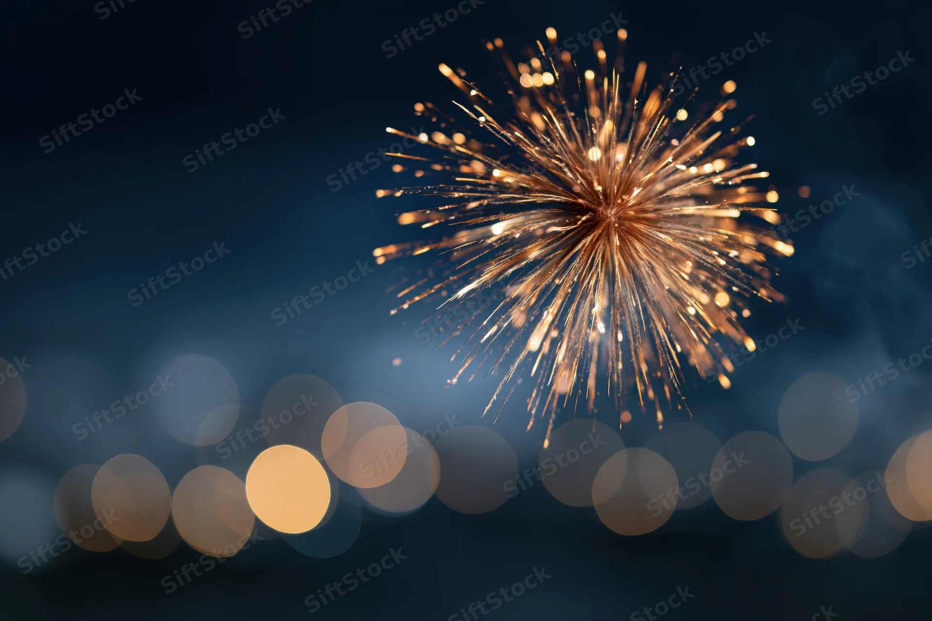 Golden firework bursting in night sky above blurred city lights