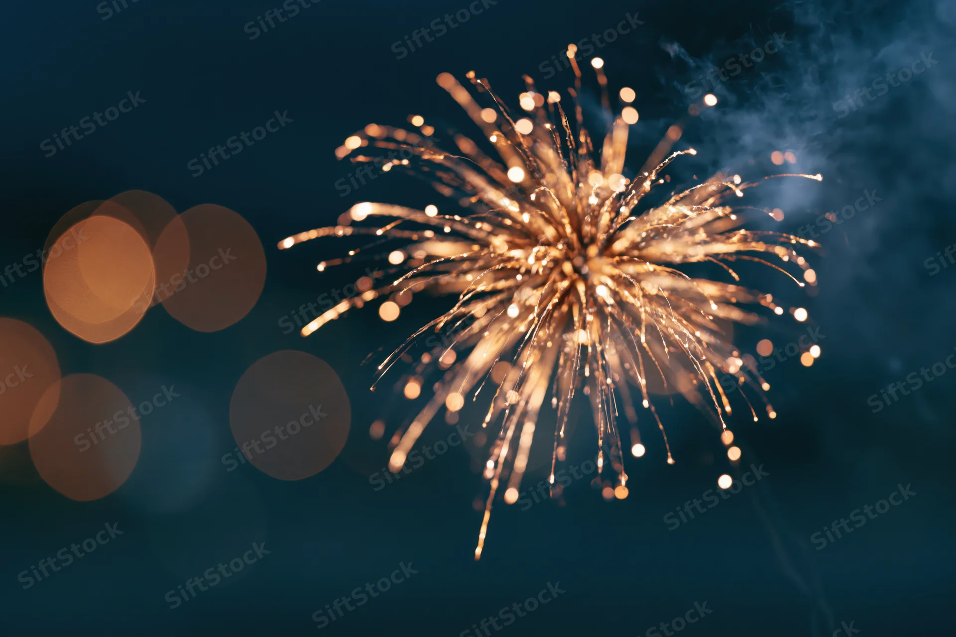 Golden firework burst exploding in the night sky with bokeh lights in the background