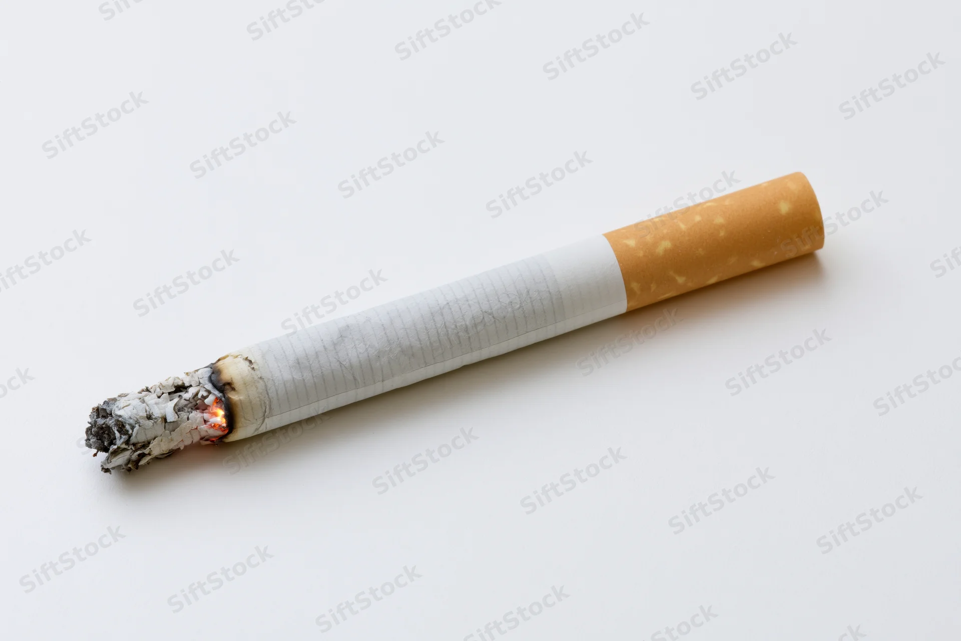 Lit cigarette with glowing ember and collapsed ash on white background