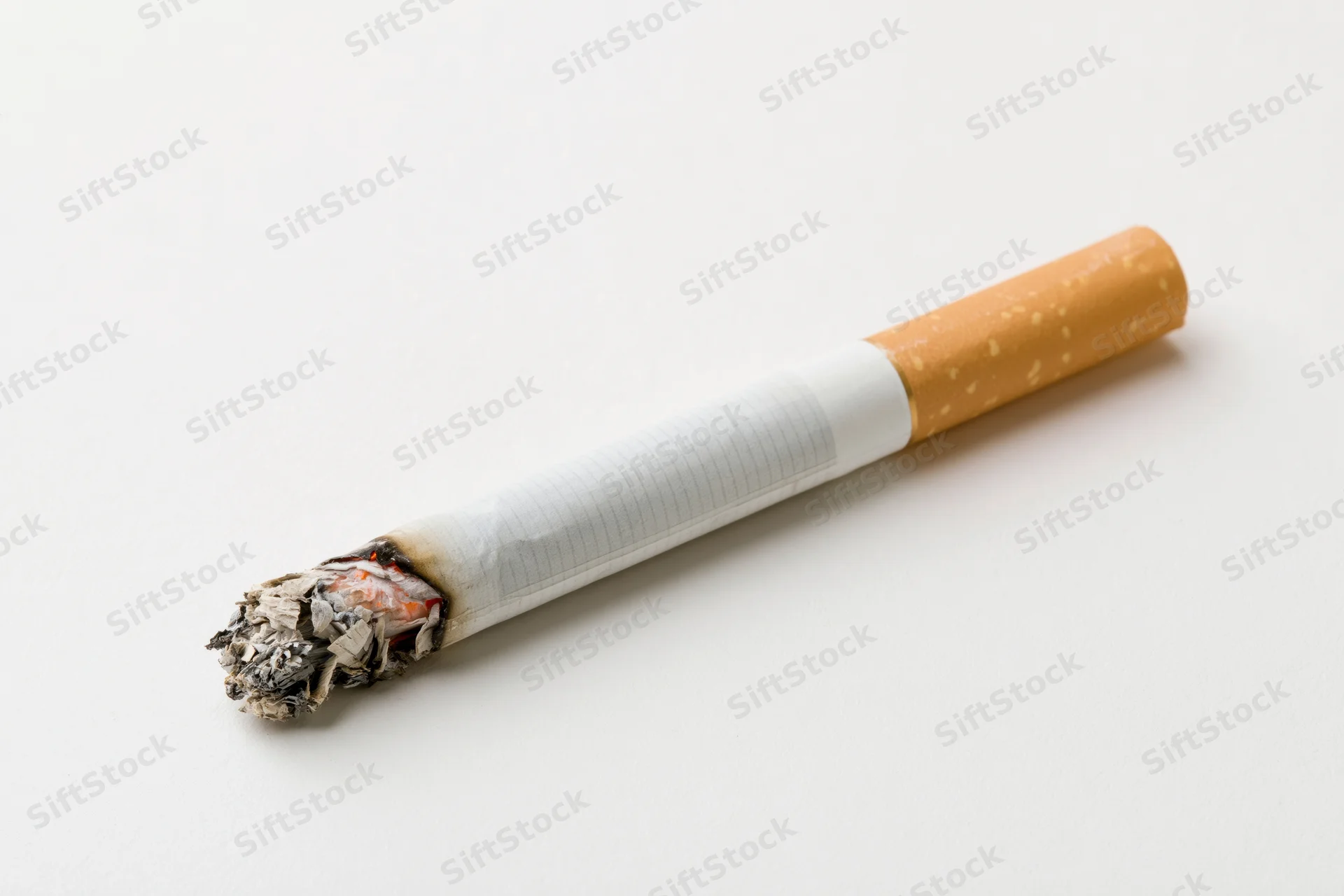 Lit cigarette with glowing ember and collapsed ash on white surface