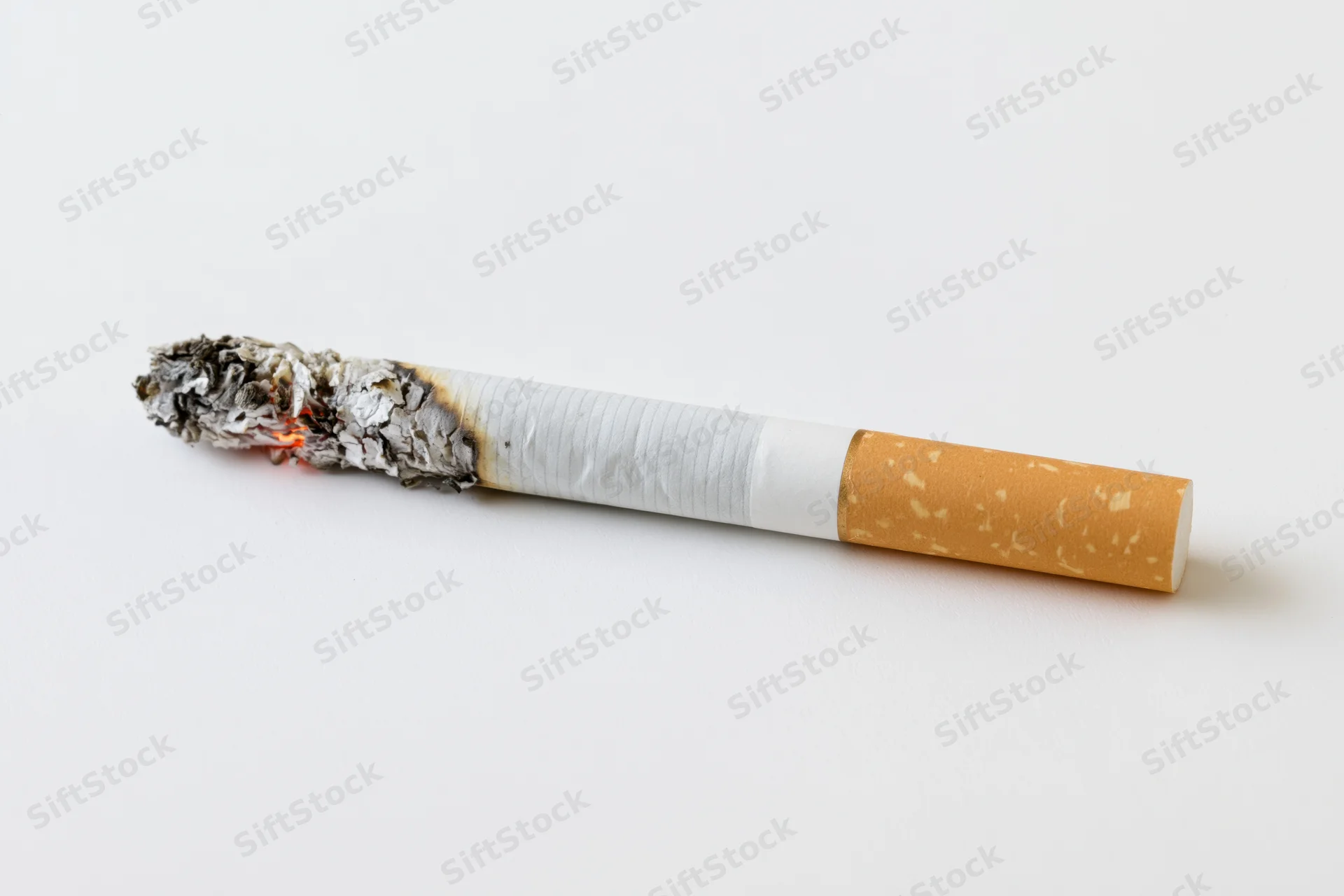 Lit cigarette with glowing ember and ash on white surface